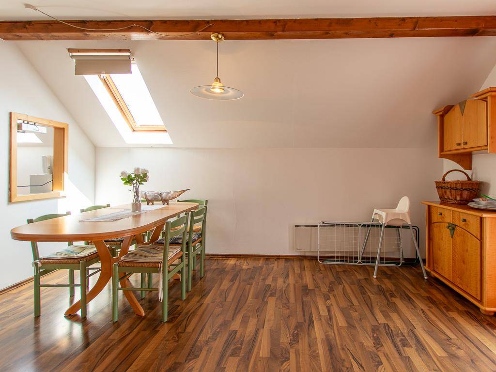 Geräumiger Essbereich mit Holztisch, Dachschräge und sichtbaren Holzbalken, hell und einladend.