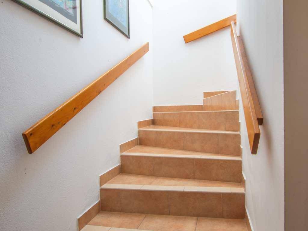 Geflieste Treppe mit Holzgeländer, die die verschiedenen Etagen des Hauses verbindet.