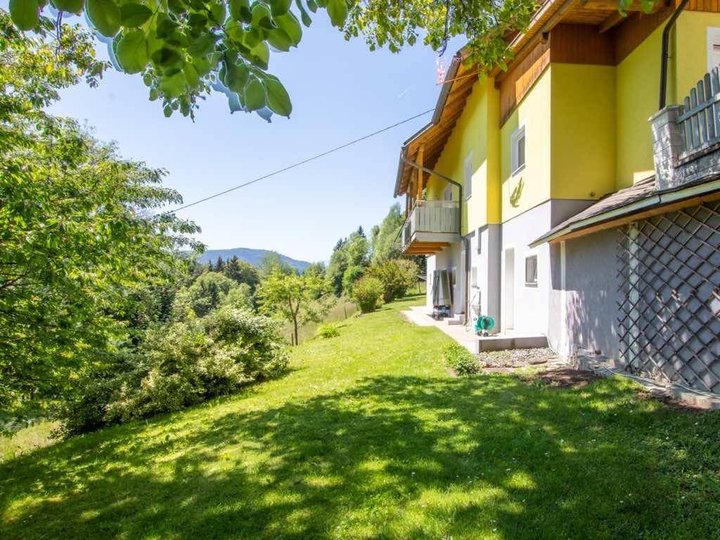 Großer, sonniger Gartenbereich am Hang mit Rasen, Bäumen und Blick in die Natur.