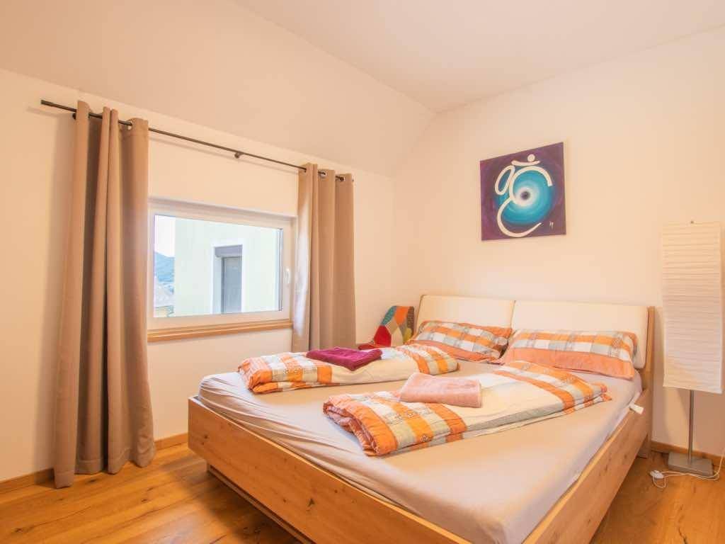 Gemütliches Schlafzimmer mit Holzbett, farbenfroher Bettwäsche und einem Fenster.
