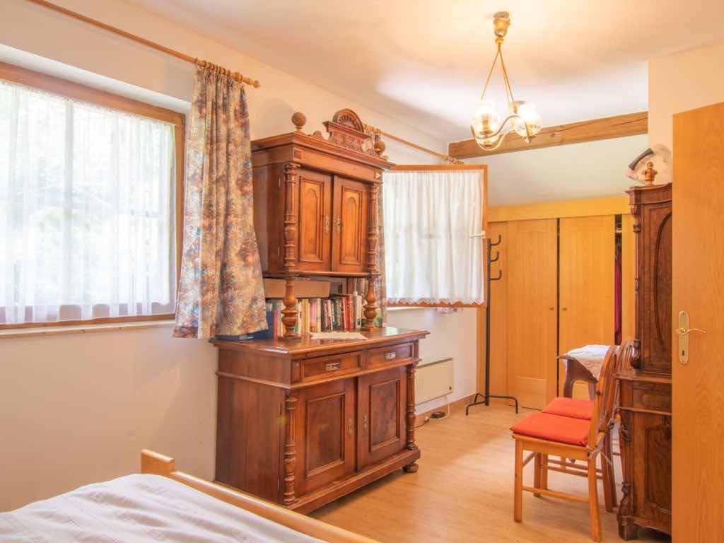 Schlafzimmer mit traditionellem Holzschrank, Doppelbett und Blick ins Grüne.