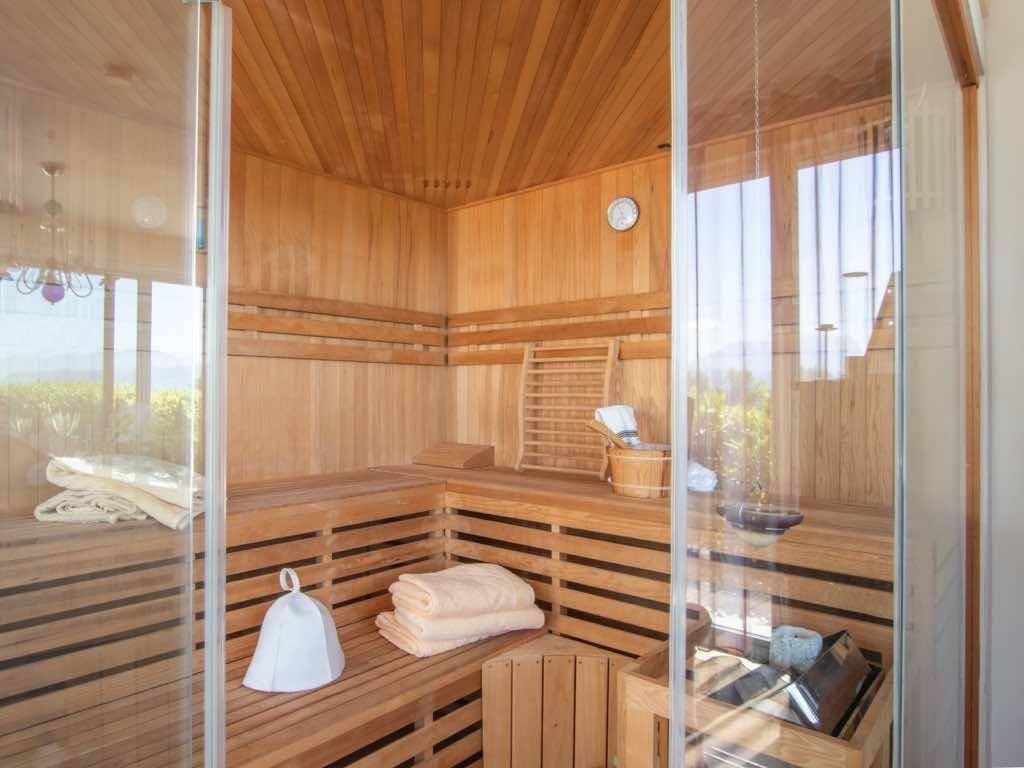 Geräumige Holzsauna mit Bänken und Glasfront, ideal zur Entspannung.