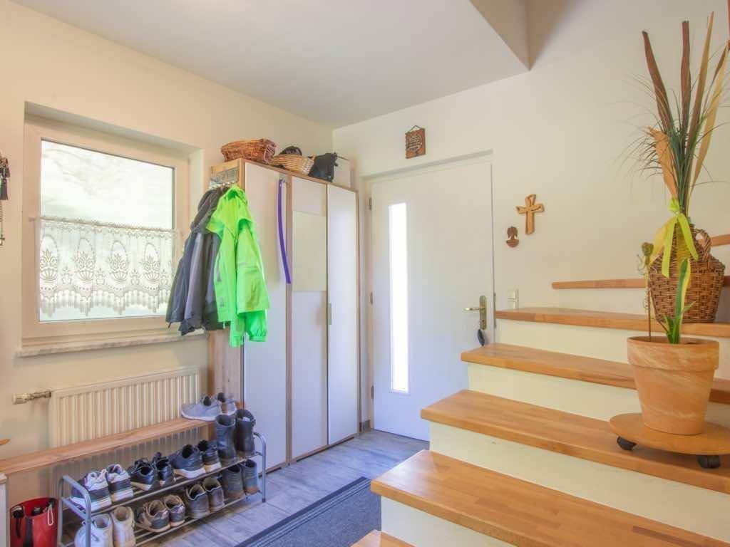 Heller Eingangsbereich mit Holztreppe, Schuhregal und Garderobenschrank.