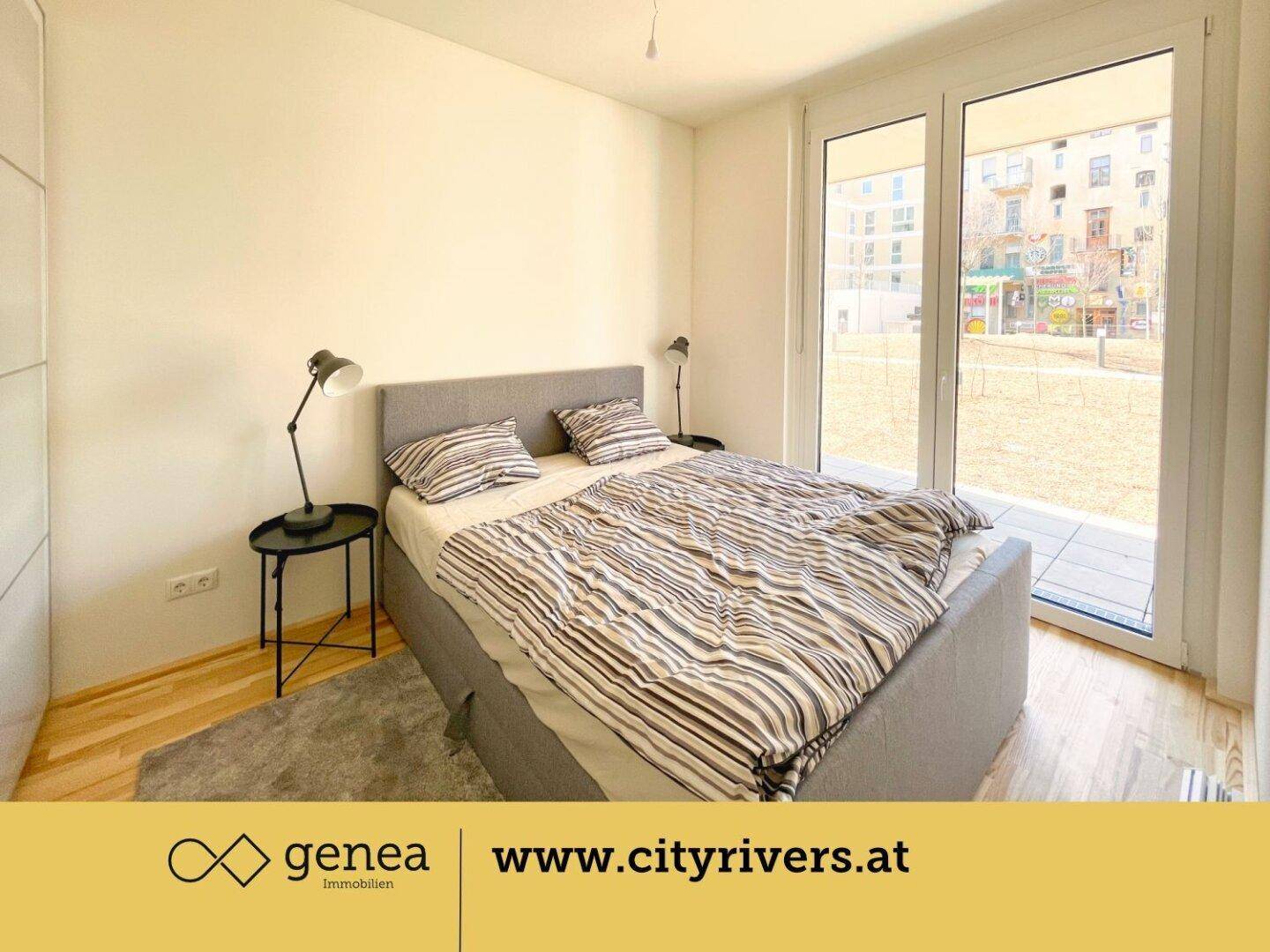 Helles Schlafzimmer mit Doppelbett, Holzboden und großen Fenstern mit Zugang zum Außenbereich.