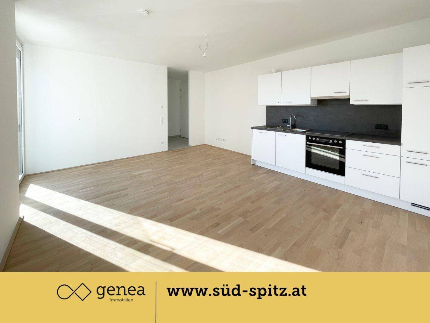 Geräumige, unmöblierte Wohnküche mit neuen weißen Einbauschränken und Holzboden.