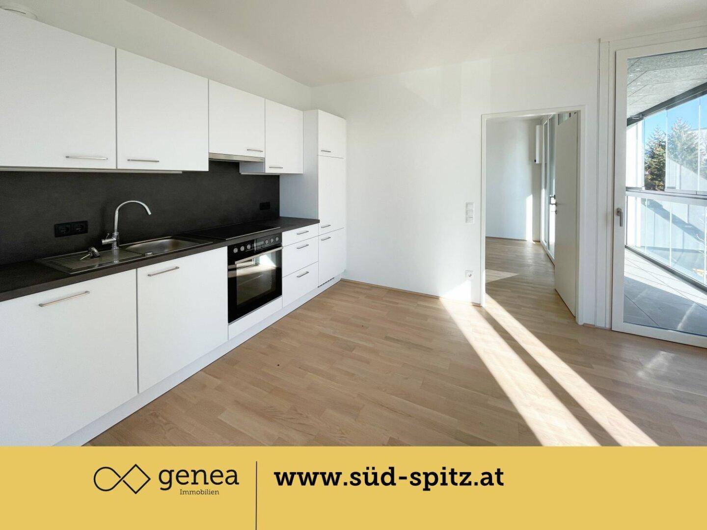 Moderne Einbauküche mit weißen Schränken, dunkler Arbeitsplatte und Holzboden.