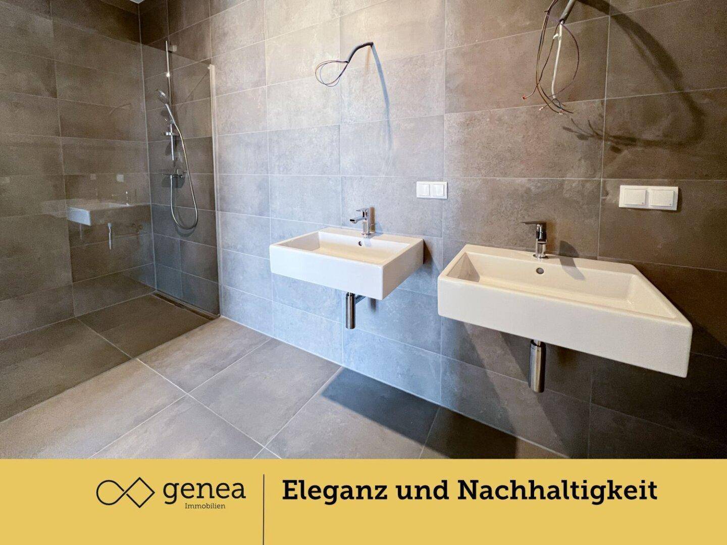 Geräumiges Badezimmer mit zwei Waschbecken und einer großen, ebenerdigen Dusche, komplett gefliest.