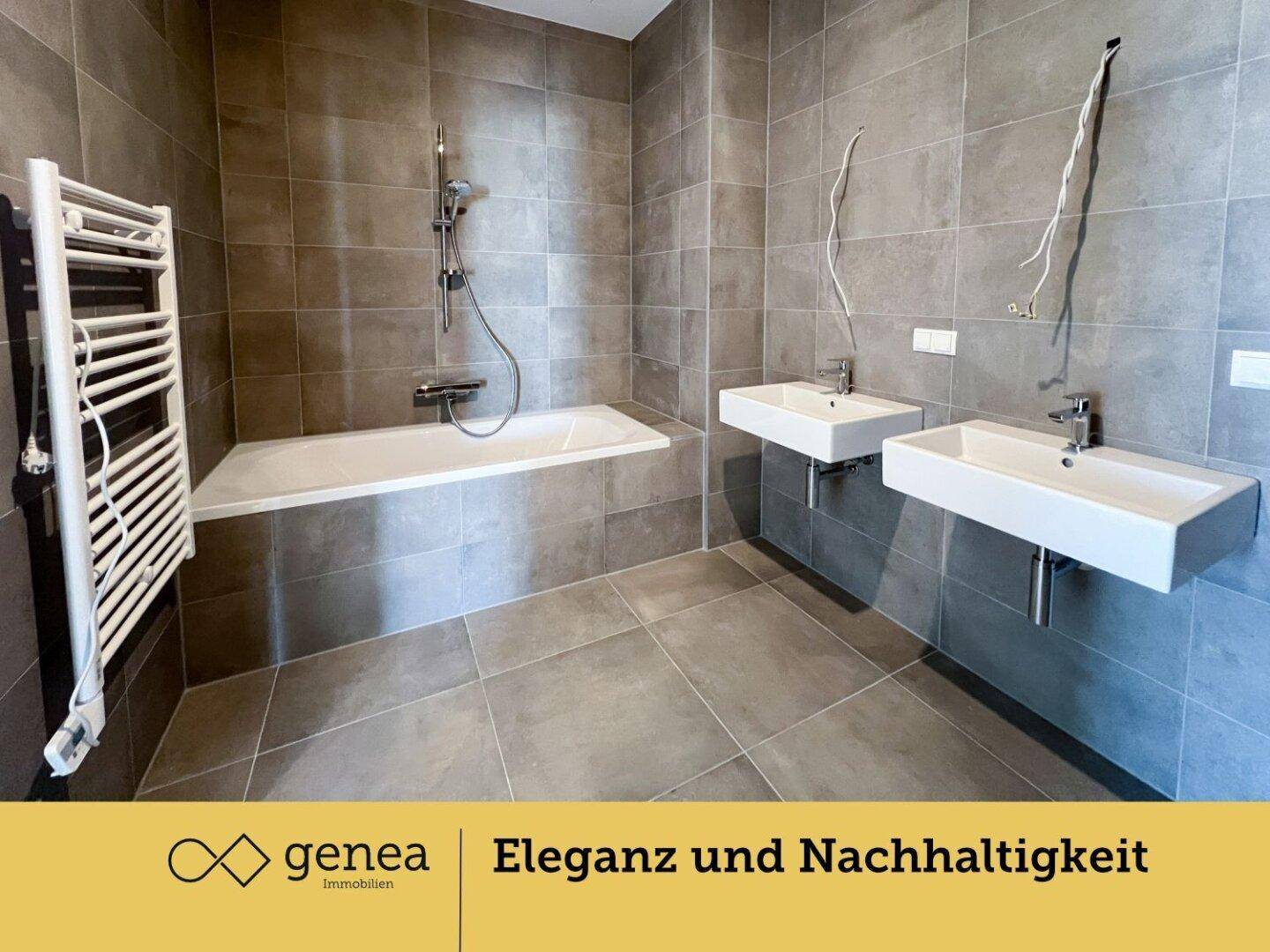 Modernes Badezimmer mit zwei Waschbecken, Badewanne und grauen Fliesen.