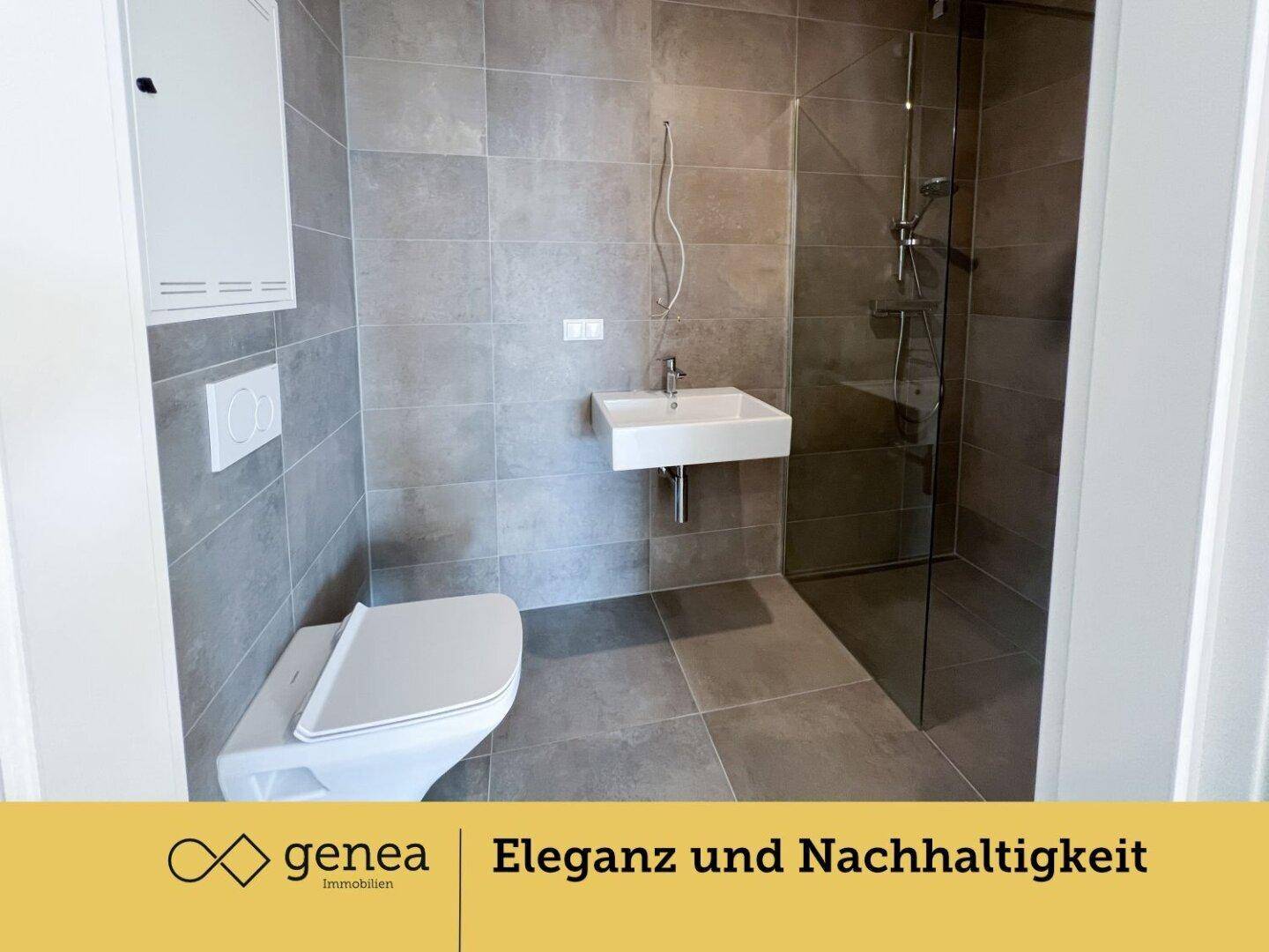 Modernes Badezimmer mit grauen Fliesen, wandhängendem WC und begehbarer Dusche.