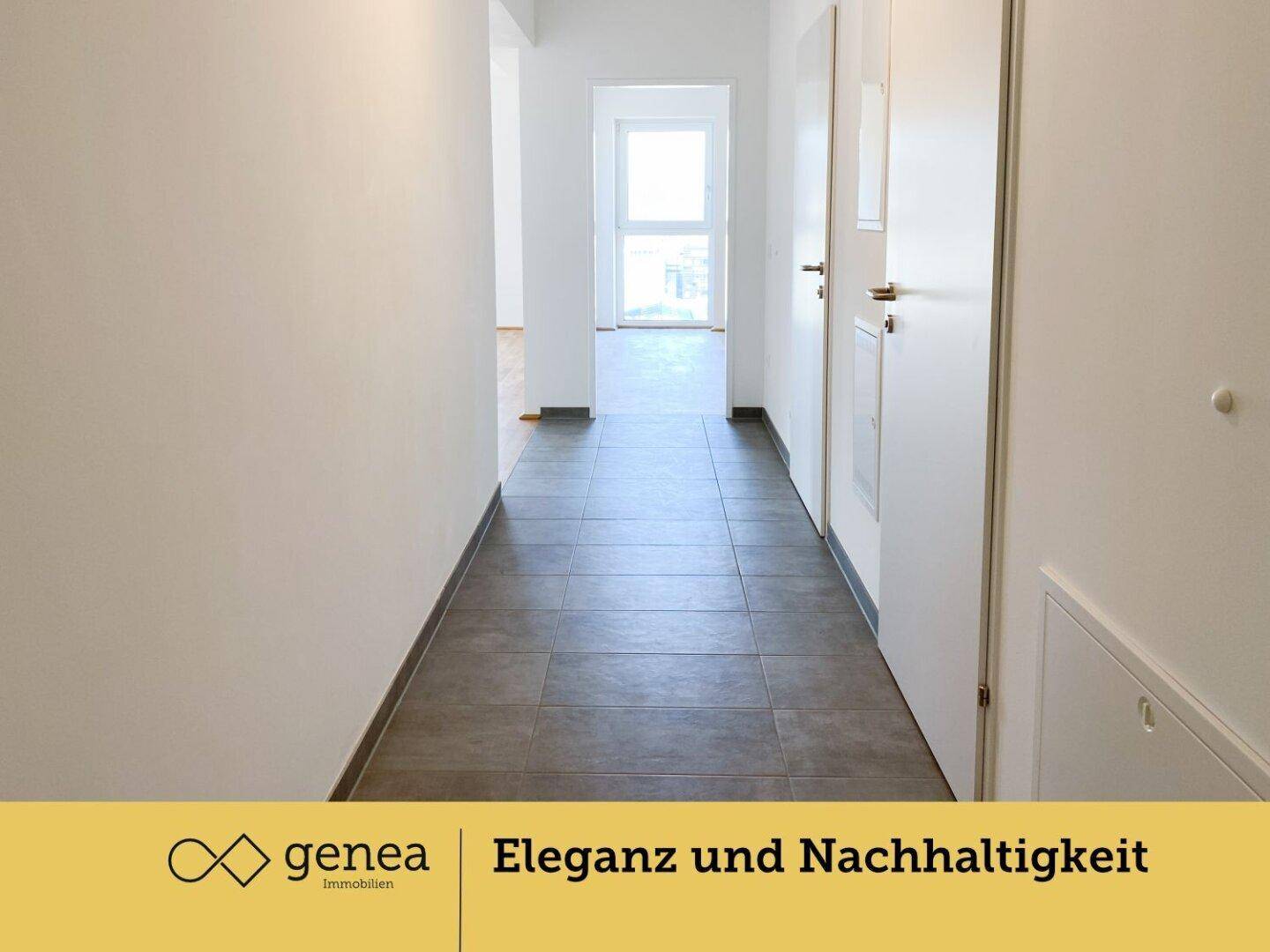 Heller Flur mit modernen Fliesen, weißen Wänden und Zugang zu weiteren Räumen.