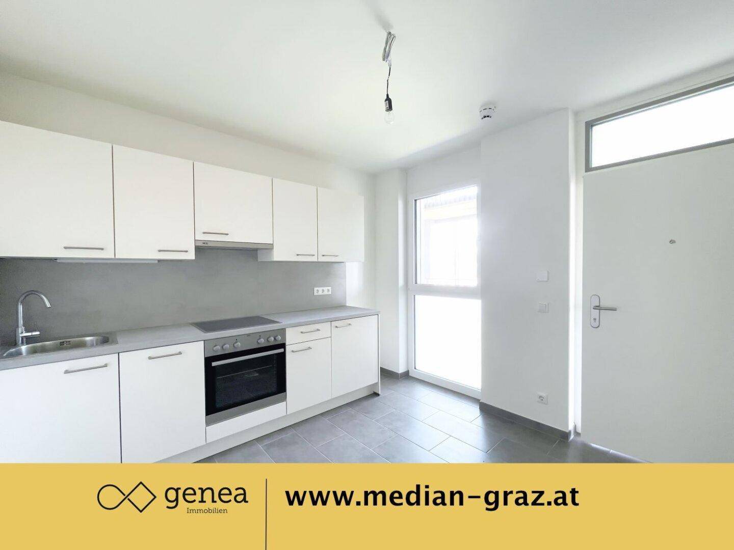 Helle Küche mit weißen Schränken, integriertem Herd und Zugang zum Balkon.