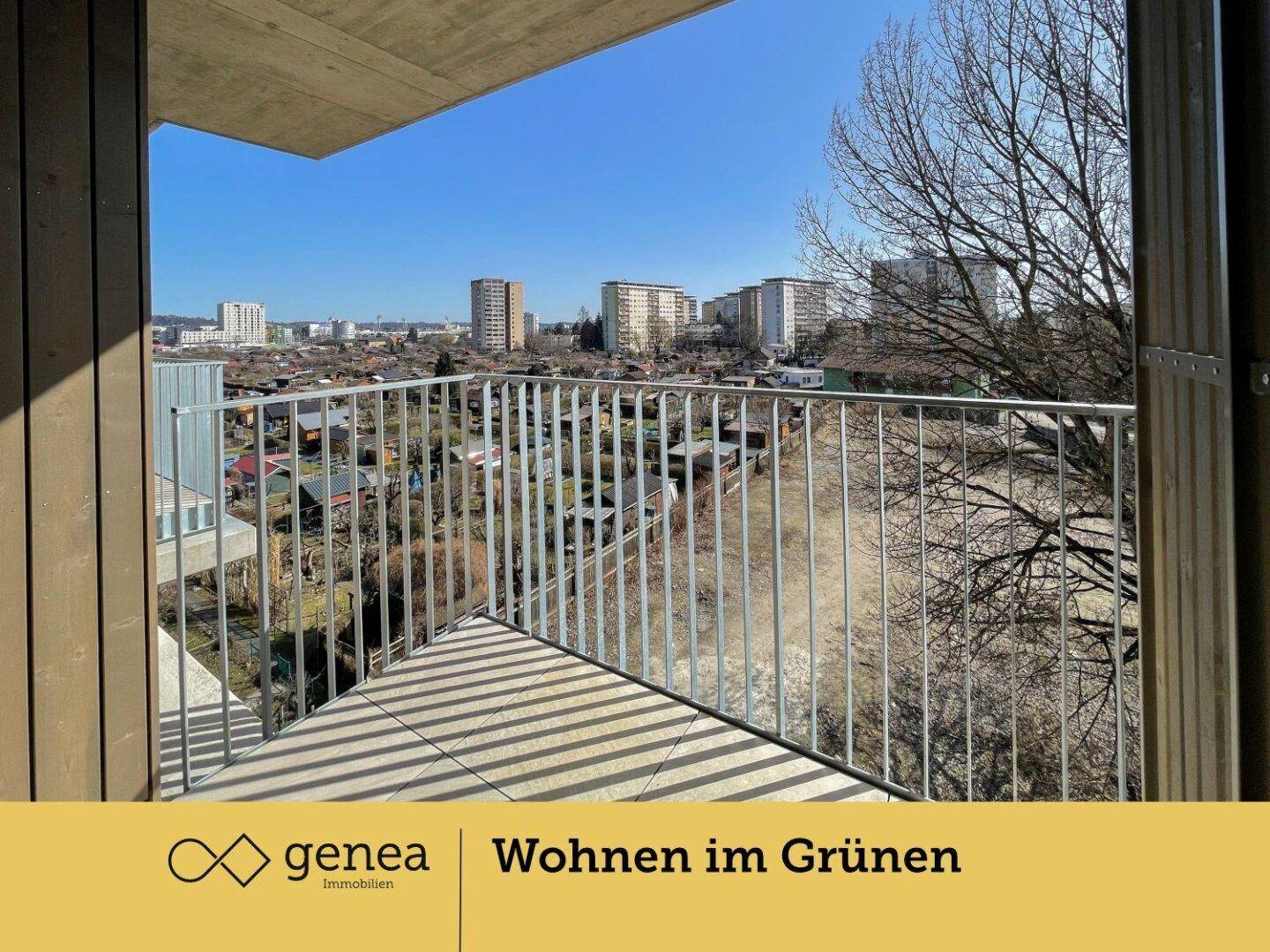 Balkon mit Metallgeländer und weitem Blick über die umliegende Wohnsiedlung und Gärten.