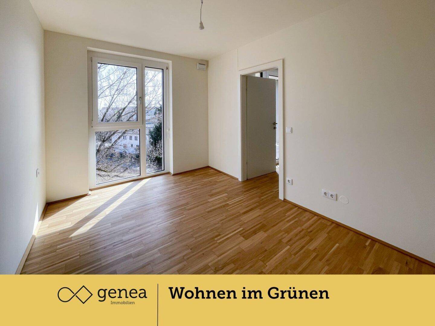 Helles Schlafzimmer mit Parkettboden und großem Fenster mit Blick ins Grüne.
