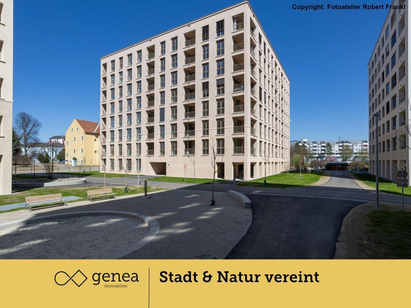 Modernes Apartmentgebäude mit heller Fassade und zahlreichen Balkonen unter blauem Himmel.