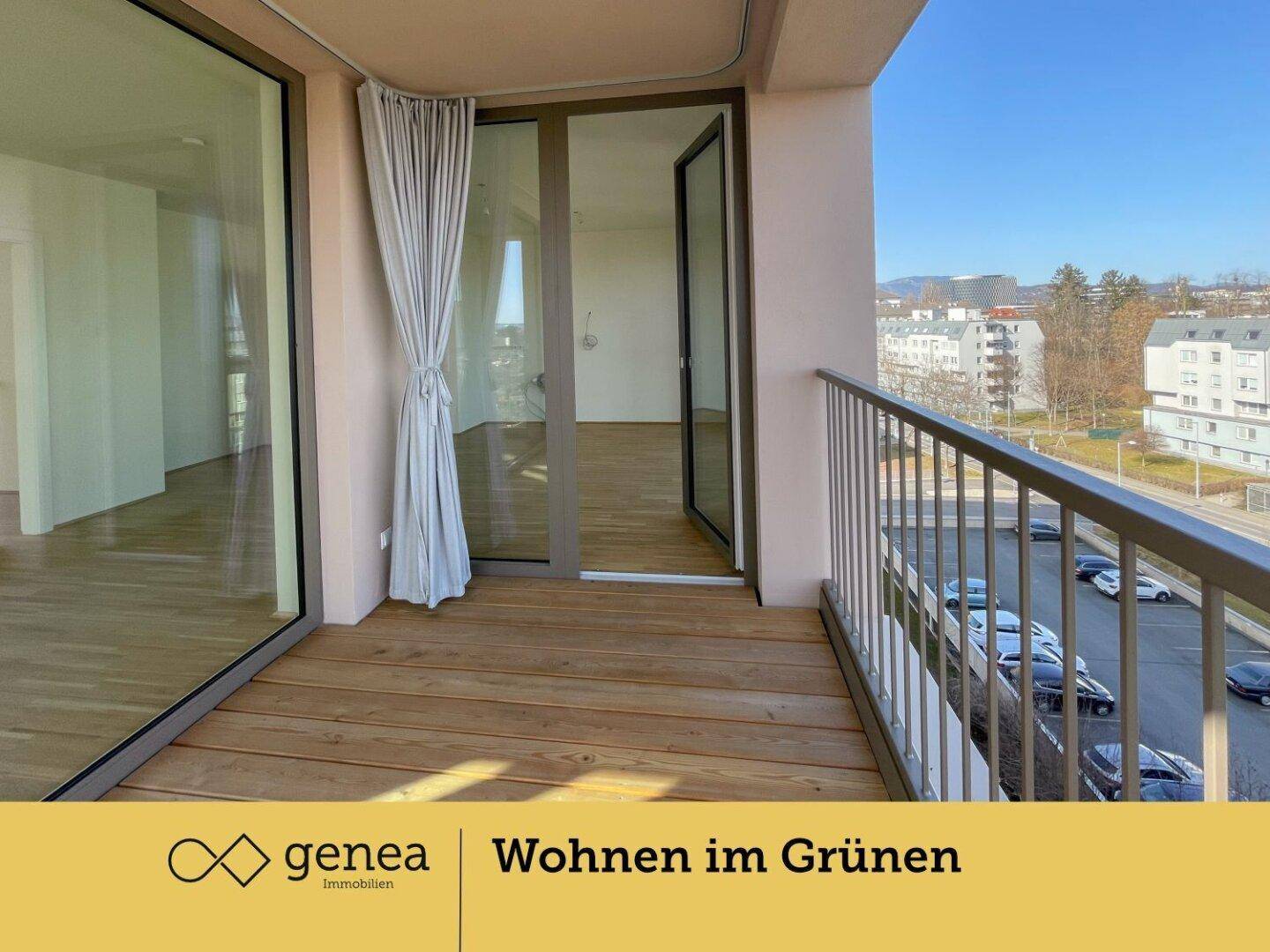 Balkon mit Holzboden und Blick auf die umliegende Wohngegend und die Berge im Hintergrund.