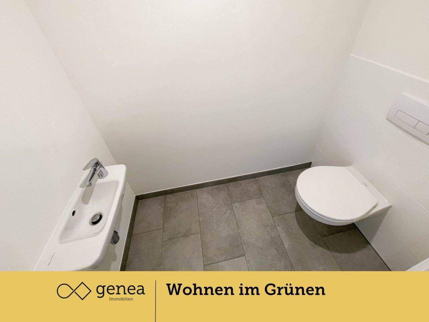 Modernes Gäste-WC mit Wand-WC, kleinem Waschbecken und grauen Fliesen.