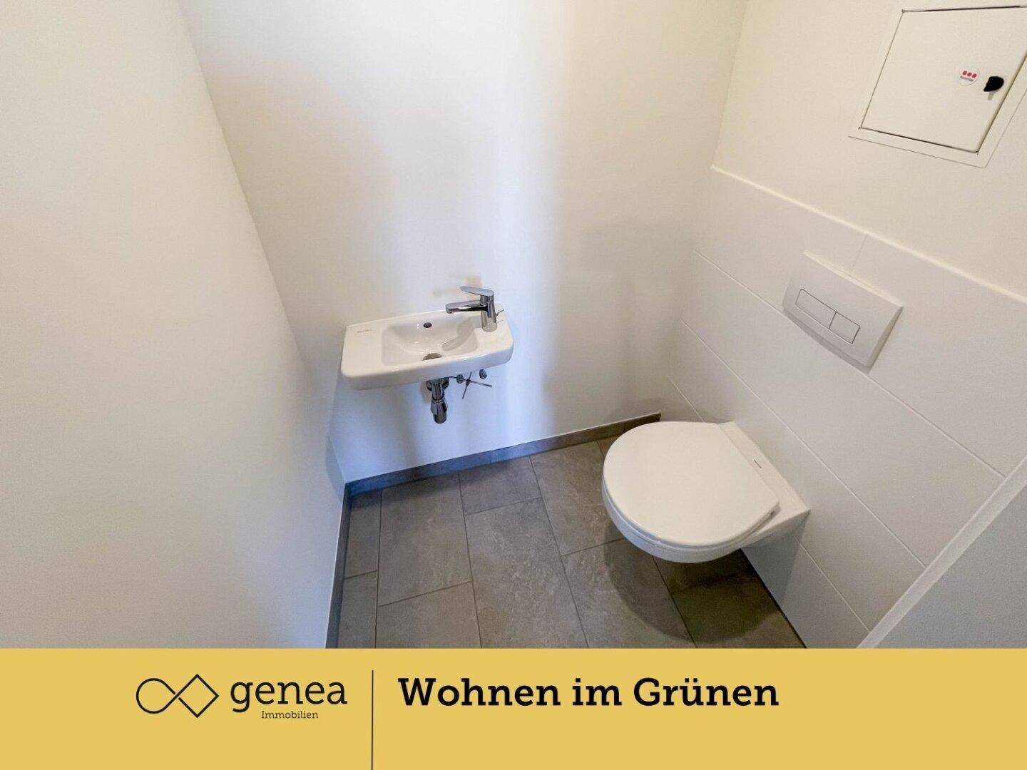 Modernes Gäste-WC mit wandhängender Toilette, kleinem Waschbecken und Fliesenboden.