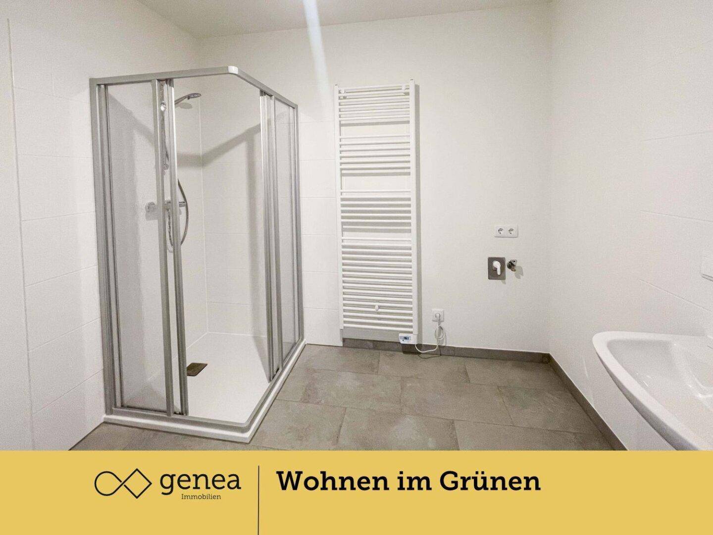 Badezimmer mit Duschkabine, Handtuchheizkörper und Anschluss für eine Waschmaschine.