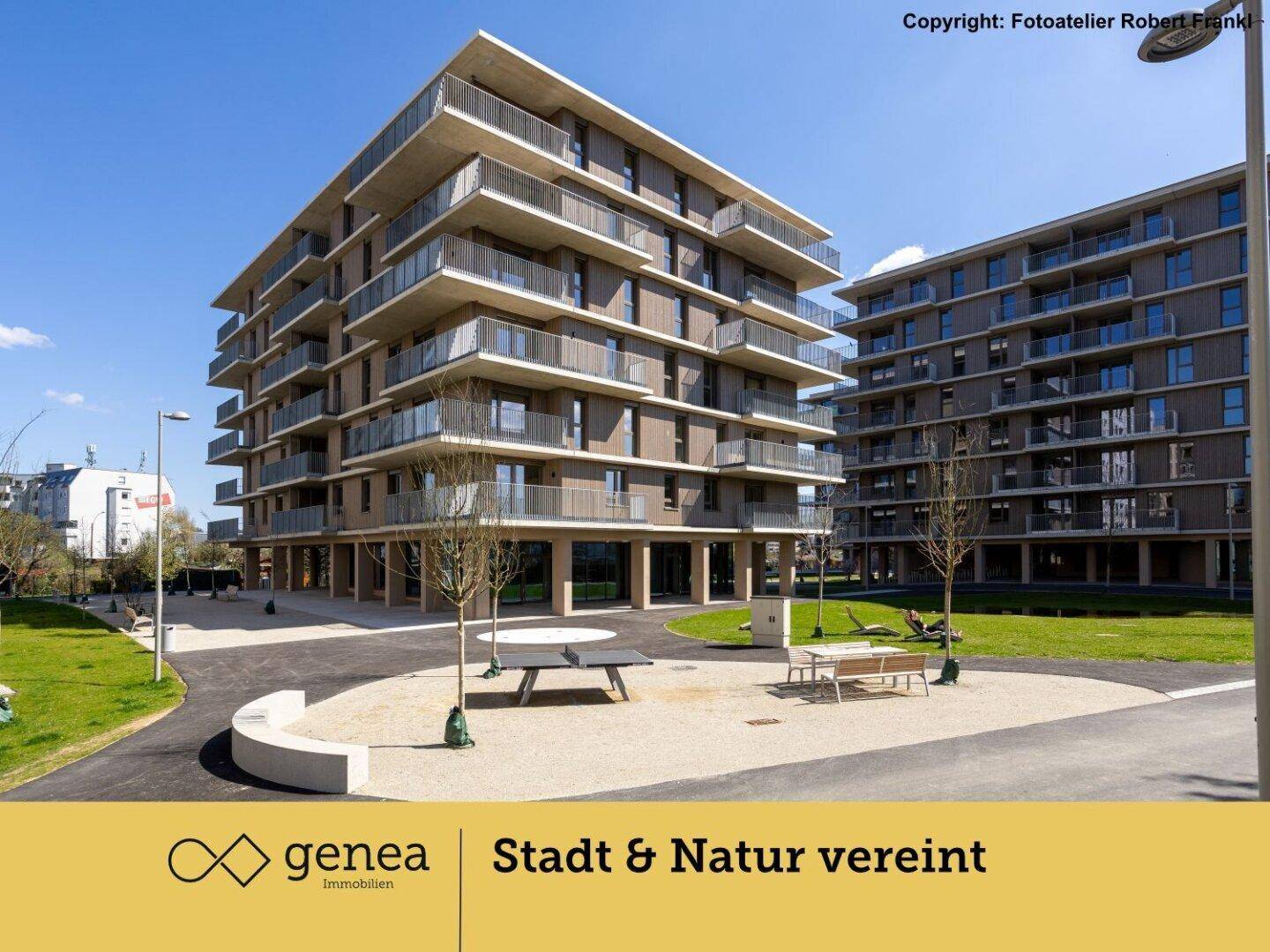Moderne Wohnanlage mit Grünflächen, Sitzgelegenheiten und Tischtennisplatte im Freien.