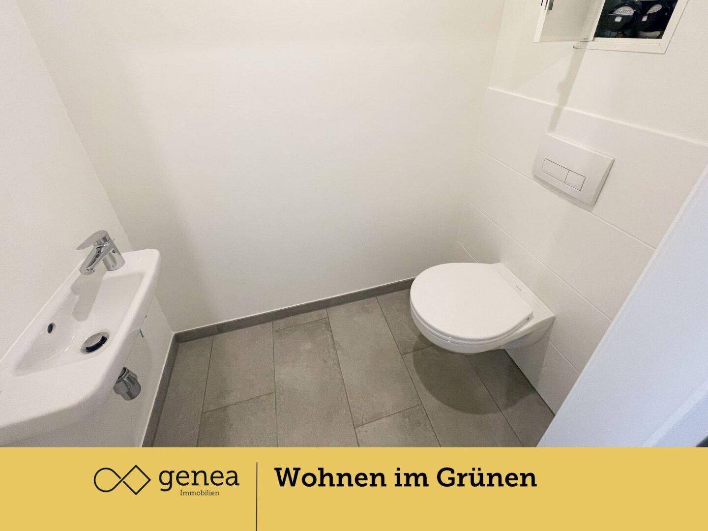 Modernes Gäste-WC mit wandhängendem WC, kleinem Waschbecken und hellen Fliesen.