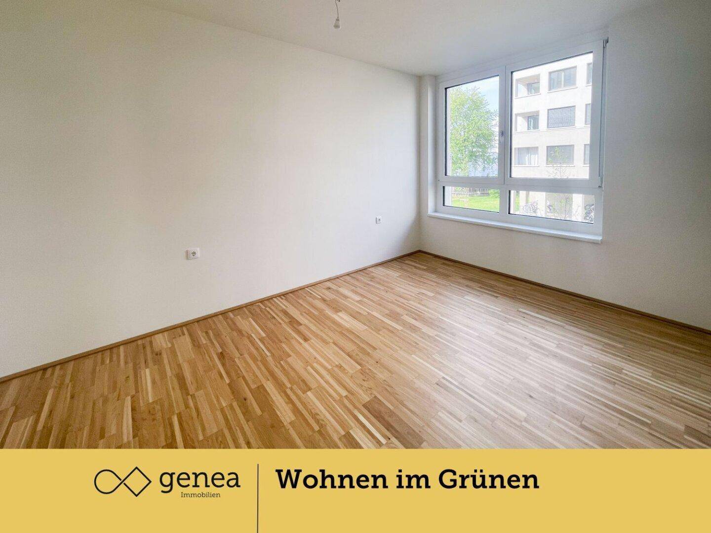 Helles Schlafzimmer mit Parkettboden und großem Fenster, das viel Tageslicht hereinlässt.