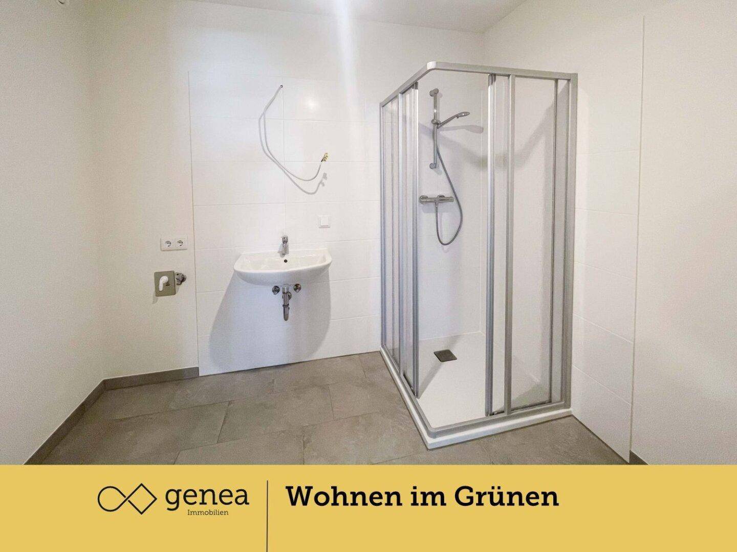 Badezimmer mit Duschkabine, Waschbecken und Fliesenboden, vorbereitet für eine Waschmaschine.