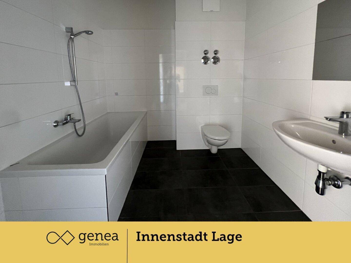Modernes Badezimmer mit dunklen Fliesen, weiß gefliesten Wänden, Badewanne und wandhängendem WC.