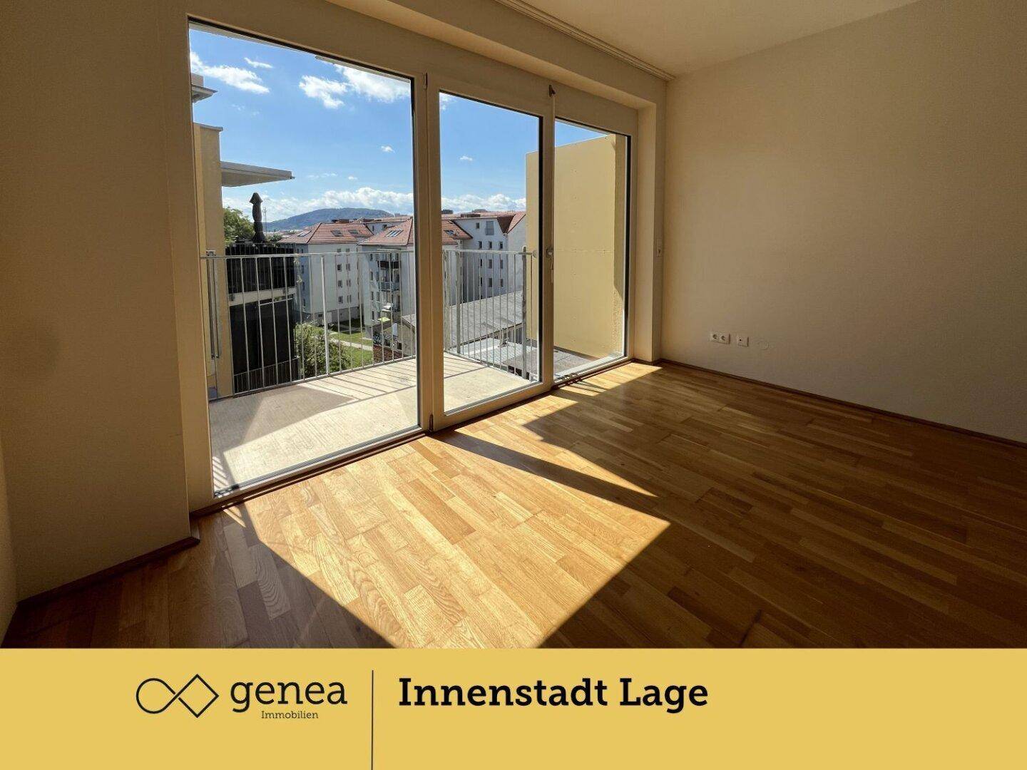 Geräumiges Zimmer mit Holzboden und viel Tageslicht durch die Balkontür, mit Blick nach draußen.