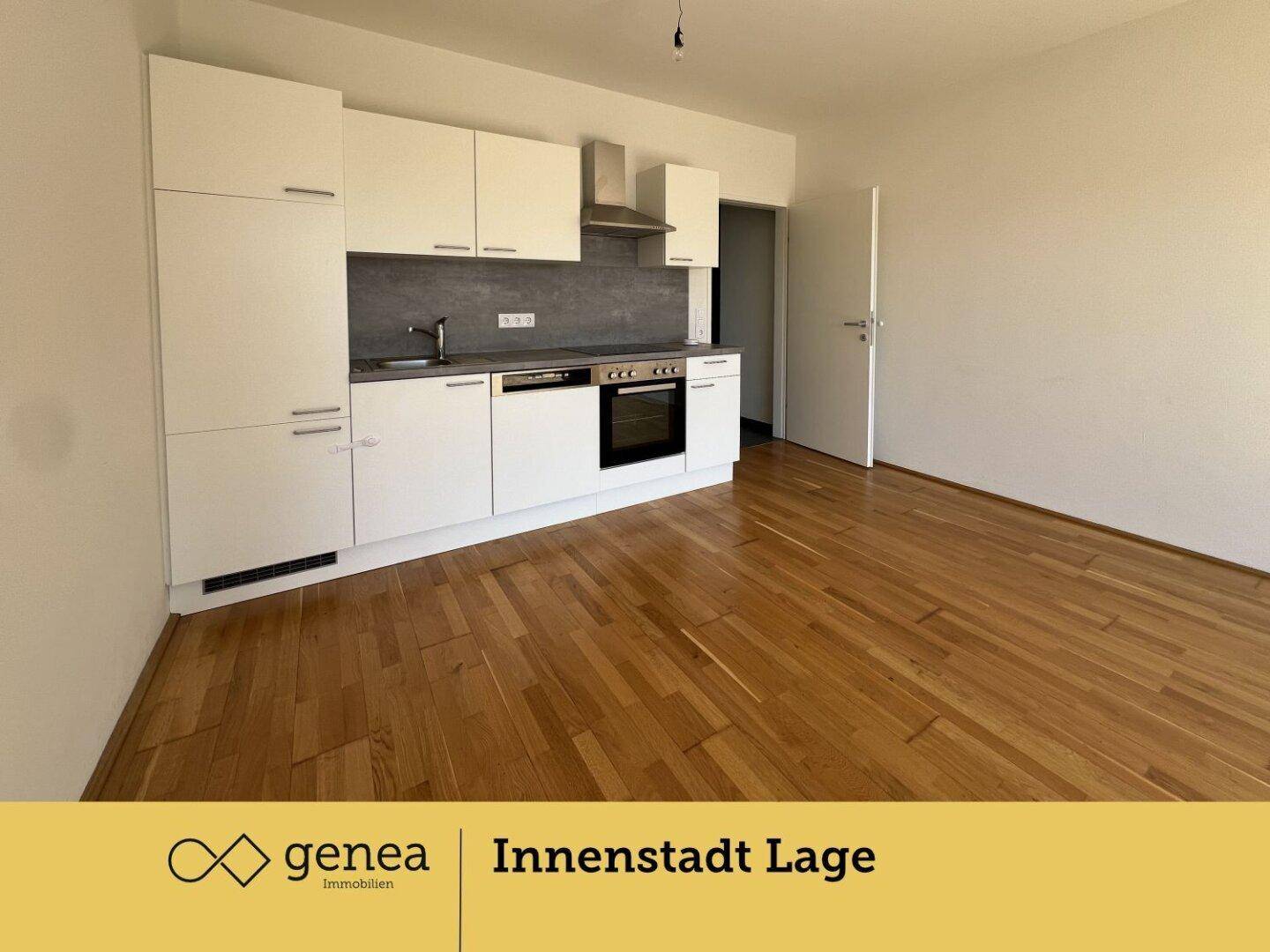 Offener Wohnbereich mit moderner Einbauküche und hellem Holzboden, ideal für geselliges Beisammensein.