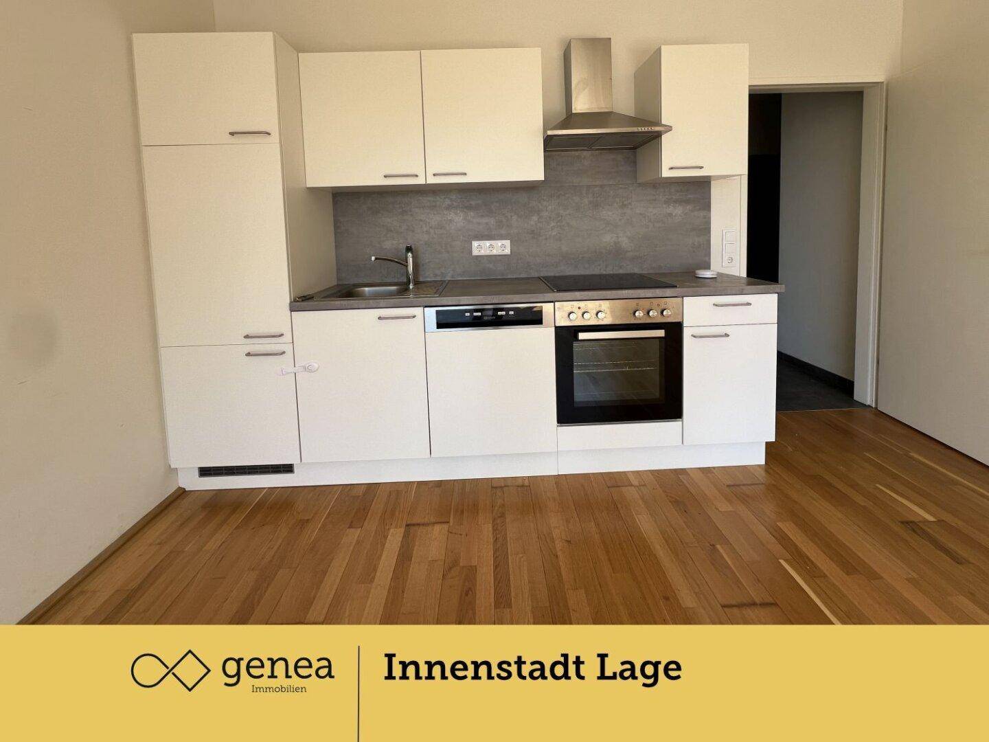 Moderne Einbauküche mit weißen Schränken, integrierten Geräten und dunkler Arbeitsplatte.
