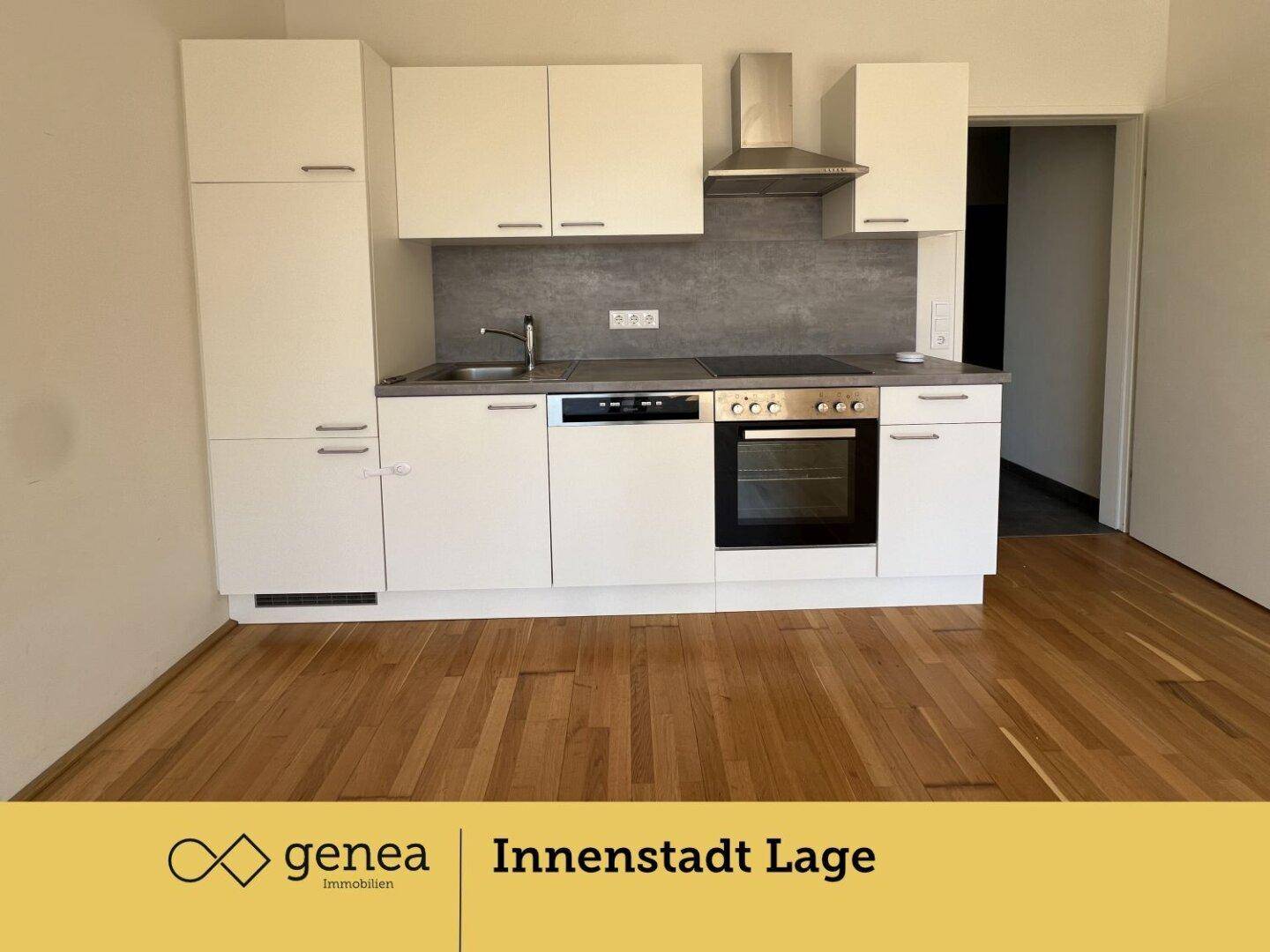 Moderne Einbauküche mit weißen Schränken, integrierten Geräten und dunkler Arbeitsplatte.