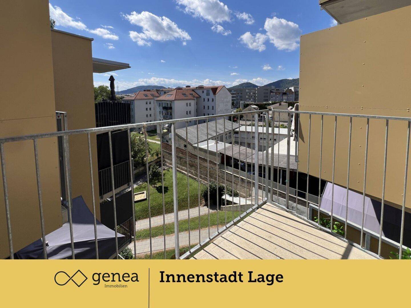 Sonniger Balkon mit weitem Blick über die Stadt und die dahinterliegende Berglandschaft.