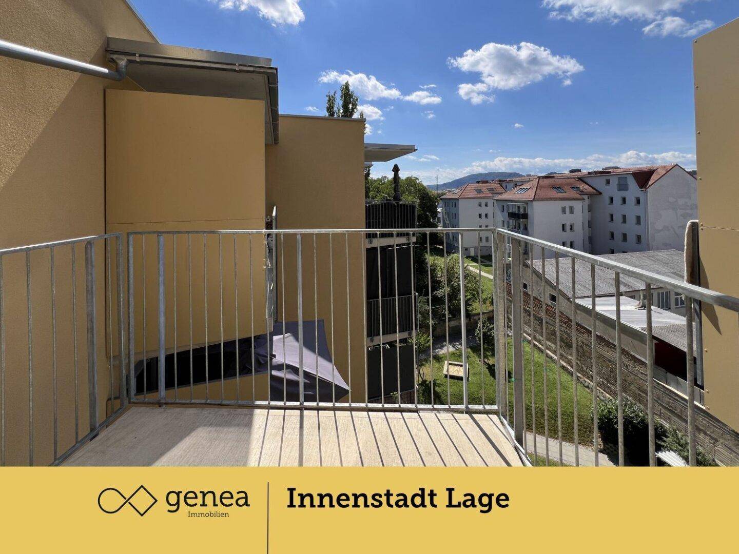 Heller Balkon mit Metallgeländer und weitem Blick auf die umliegenden Gebäude und Berge.