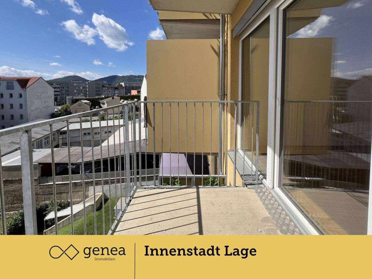 Geräumiger Balkon mit Metallgeländer und Ausblick auf die Nachbarschaft und den blauen Himmel.