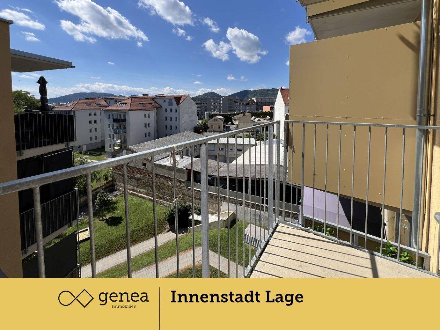 Offener Balkon mit sonniger Ausrichtung und Blick auf die städtische Umgebung und die Berge.