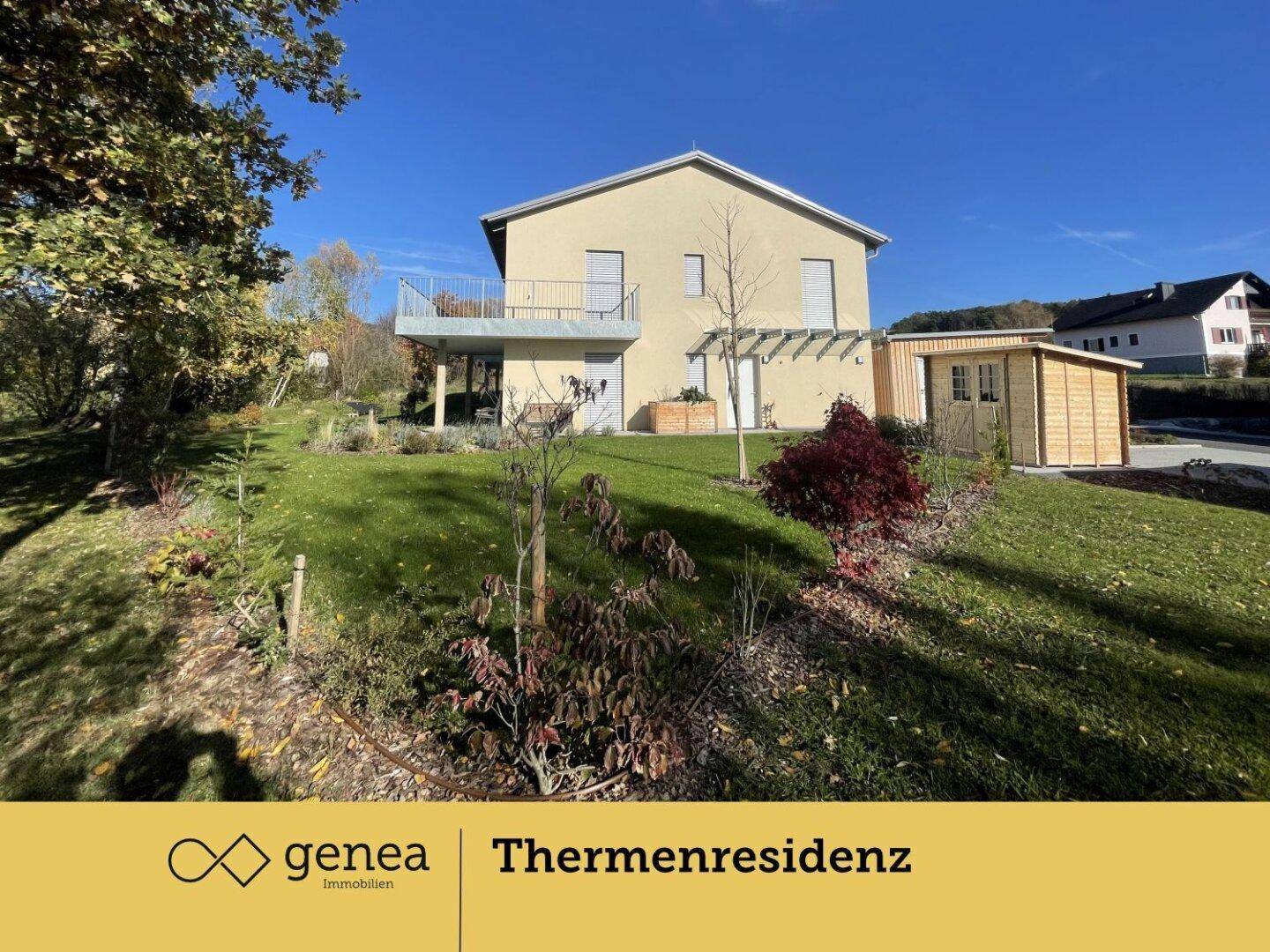 Rückseite des Hauses mit großem Garten, Gartenhaus und Balkon unter strahlend blauem Himmel.