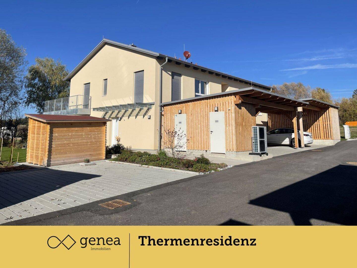Seitenansicht eines modernen Gebäudes mit Holzverkleidung, Carports, Geräteschuppen und Wärmepumpe.