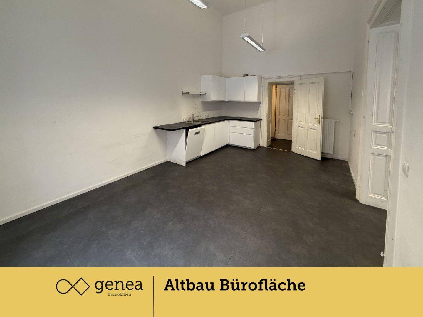 Geräumiges Büro mit integrierter Küchenzeile, dunklem Boden und weißen Wänden.