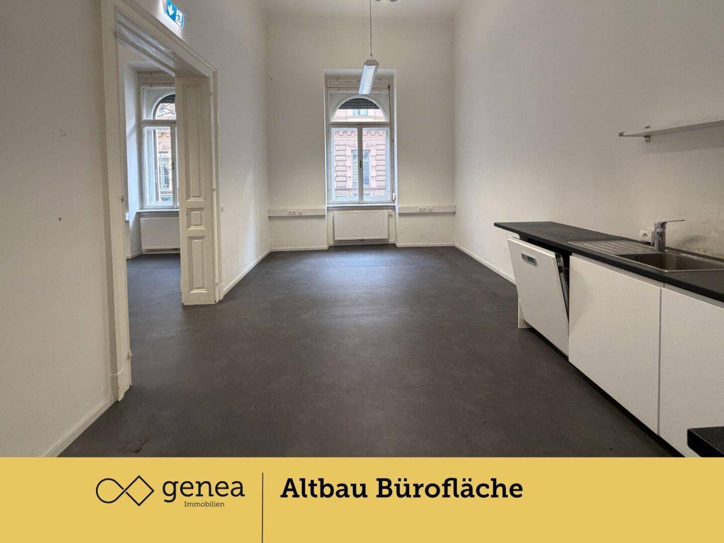 Helles Büro mit Küchenzeile und großen Fenstern, die viel Tageslicht hereinlassen.
