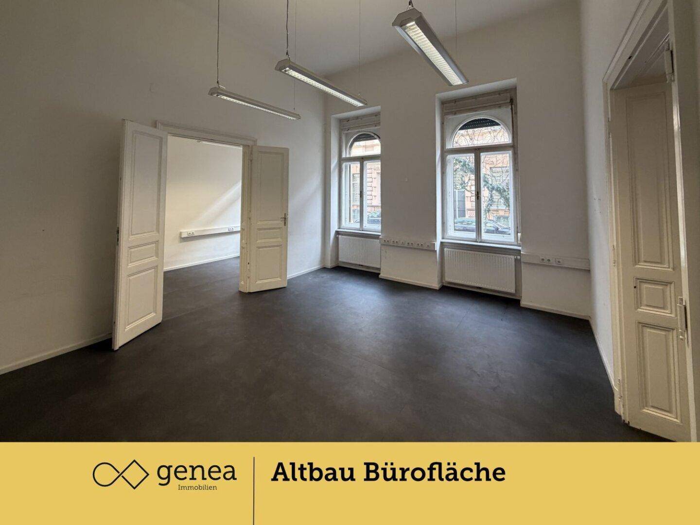 Geräumiges Büro mit hohen Decken, großen Fenstern und dunklem Bodenbelag.