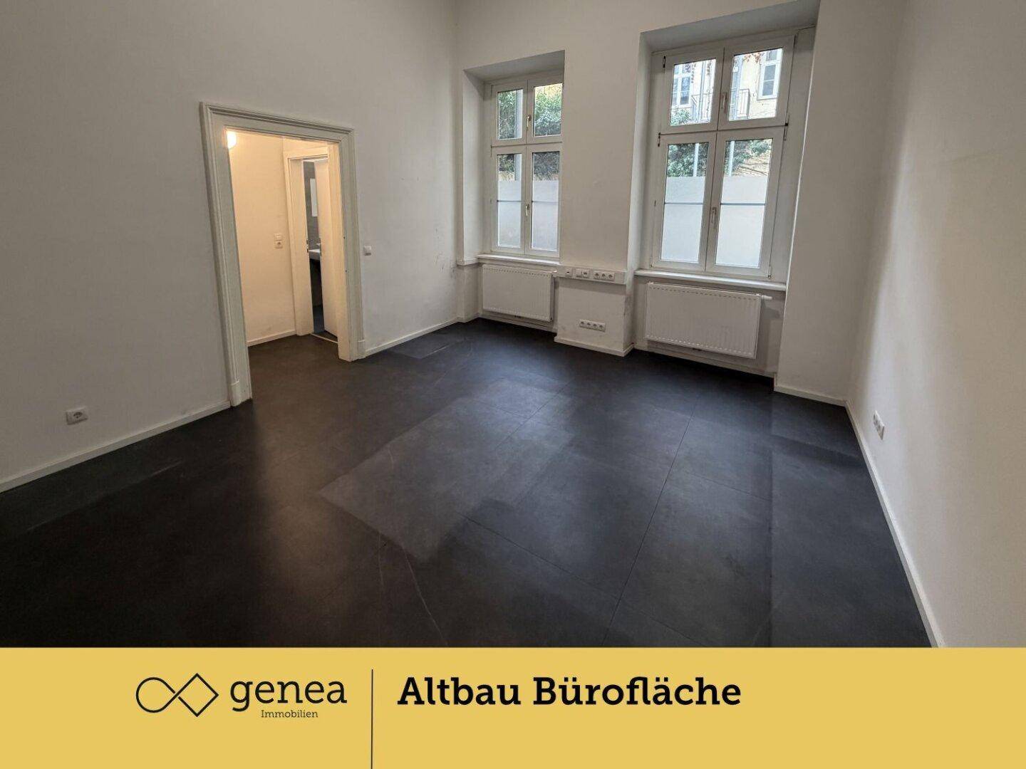 Großes Büro mit viel Tageslicht durch hohe Fenster und dunklem Bodenbelag.