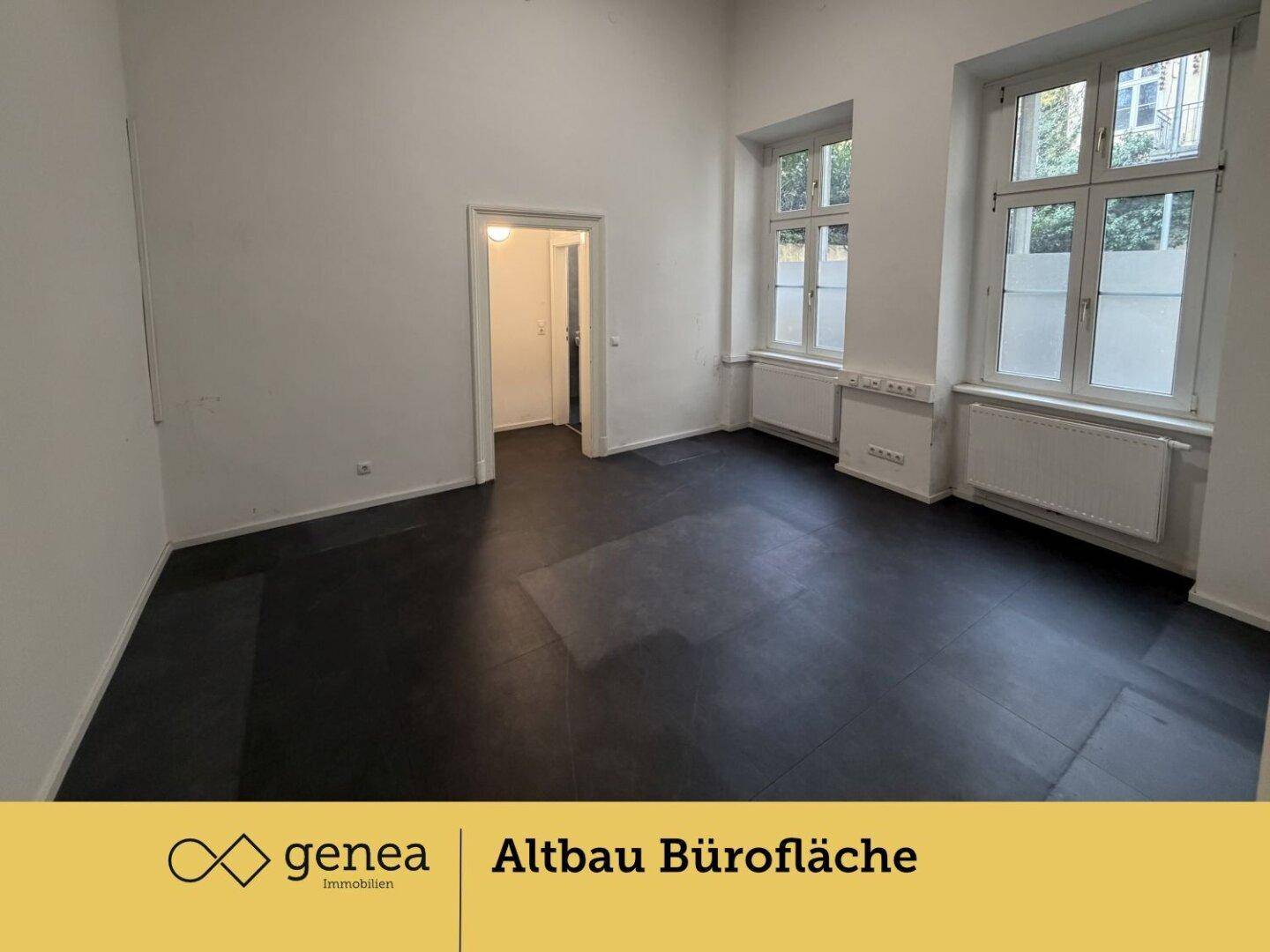 Geräumiger Büroraum mit hohen Decken, großen Fenstern und dunklem Bodenbelag, bereit zur Einrichtung.