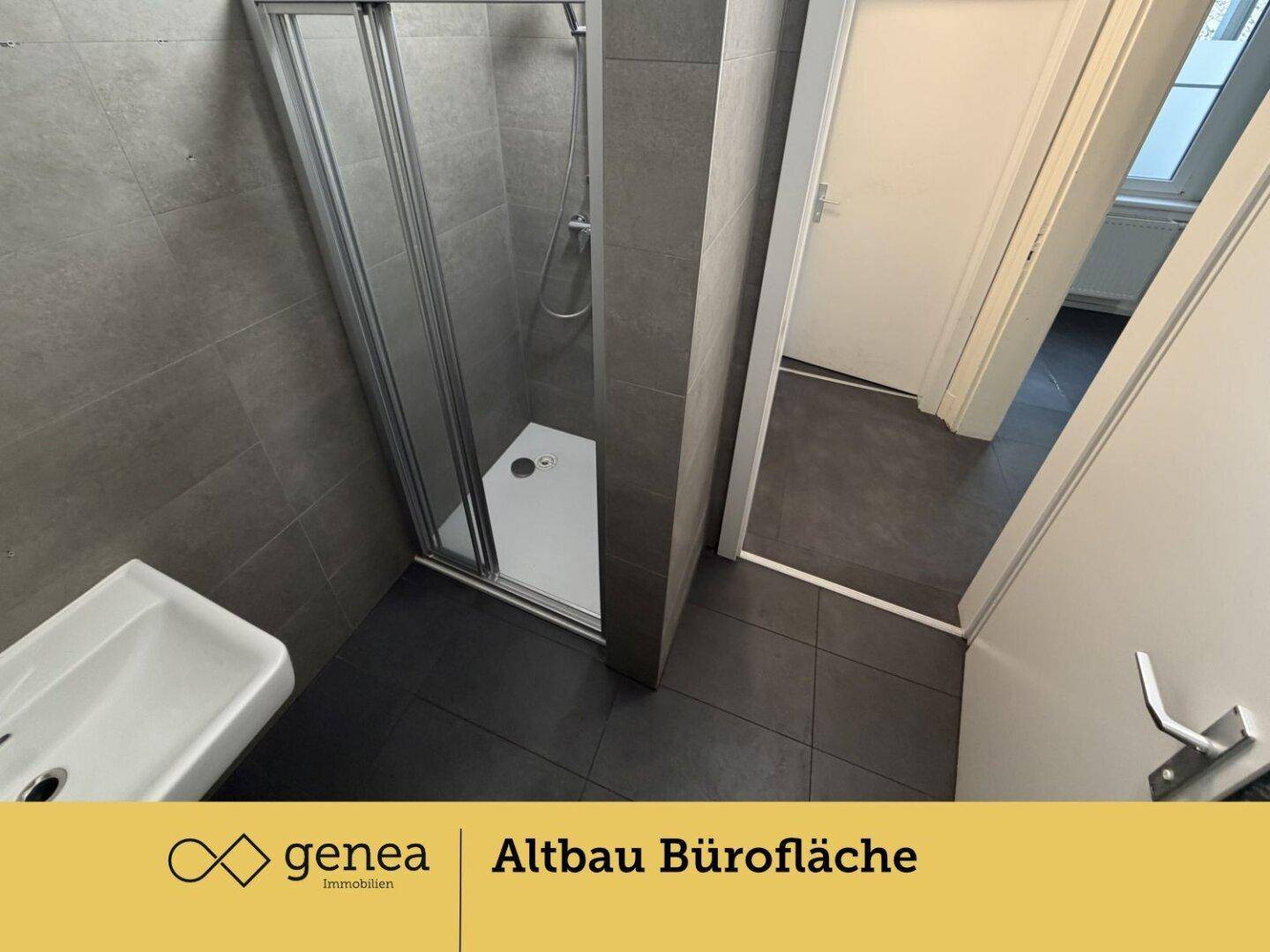 Modernes Badezimmer mit Duschkabine, Waschbecken und grauen Fliesen an Wänden und Boden.