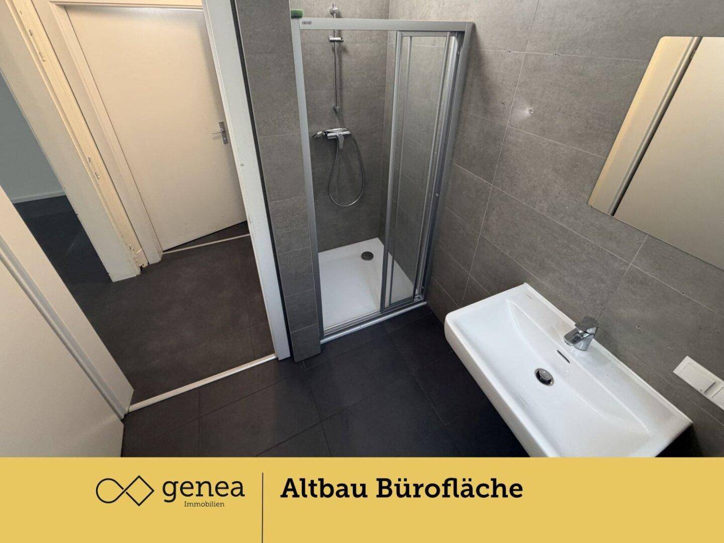 Funktionales Badezimmer mit Duschkabine, modernem Waschbecken und Spiegel, in neutralen Grautönen gehalten.