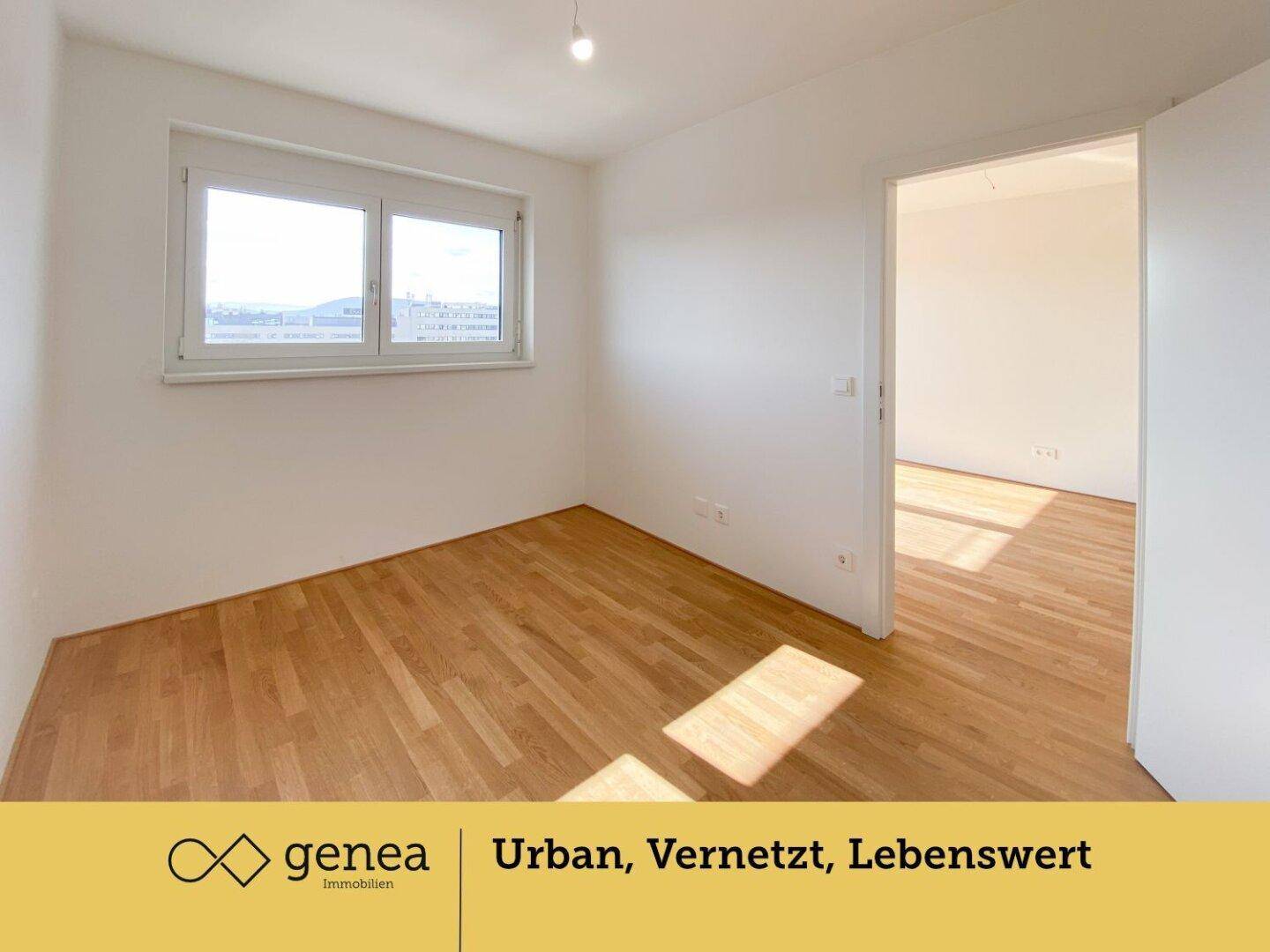 Helles Schlafzimmer mit Parkettboden und großem Fenster, das viel Tageslicht hereinlässt.