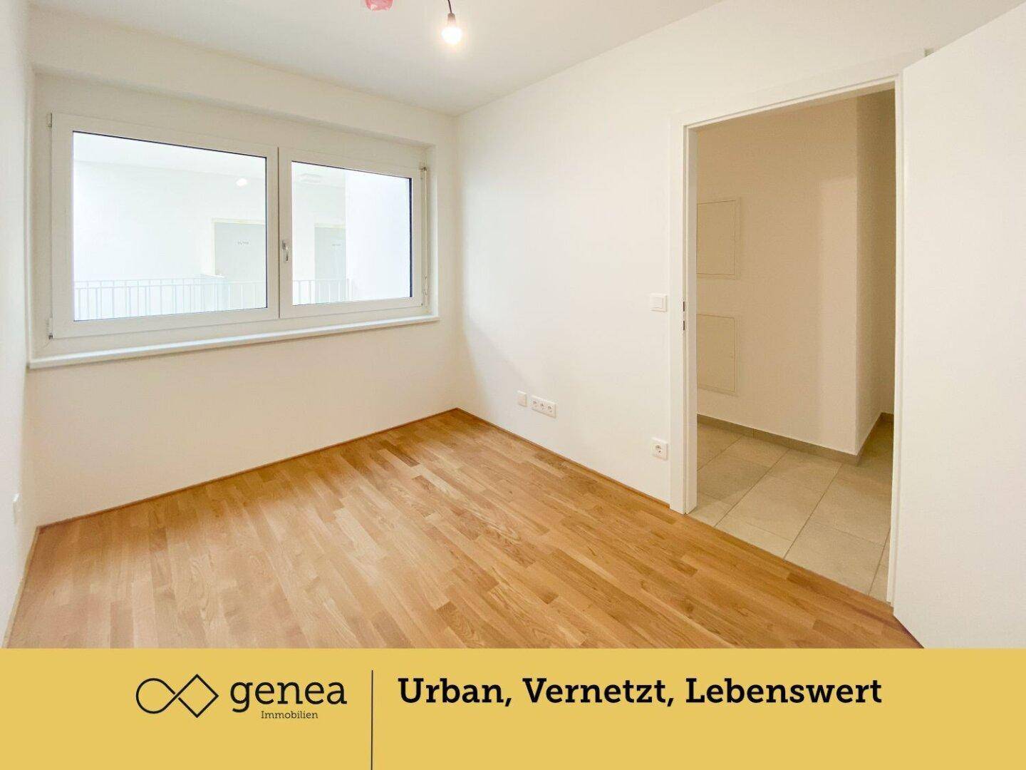 Leeres Zimmer mit hellem Parkettboden und großem Fenster, das viel Tageslicht hereinlässt.