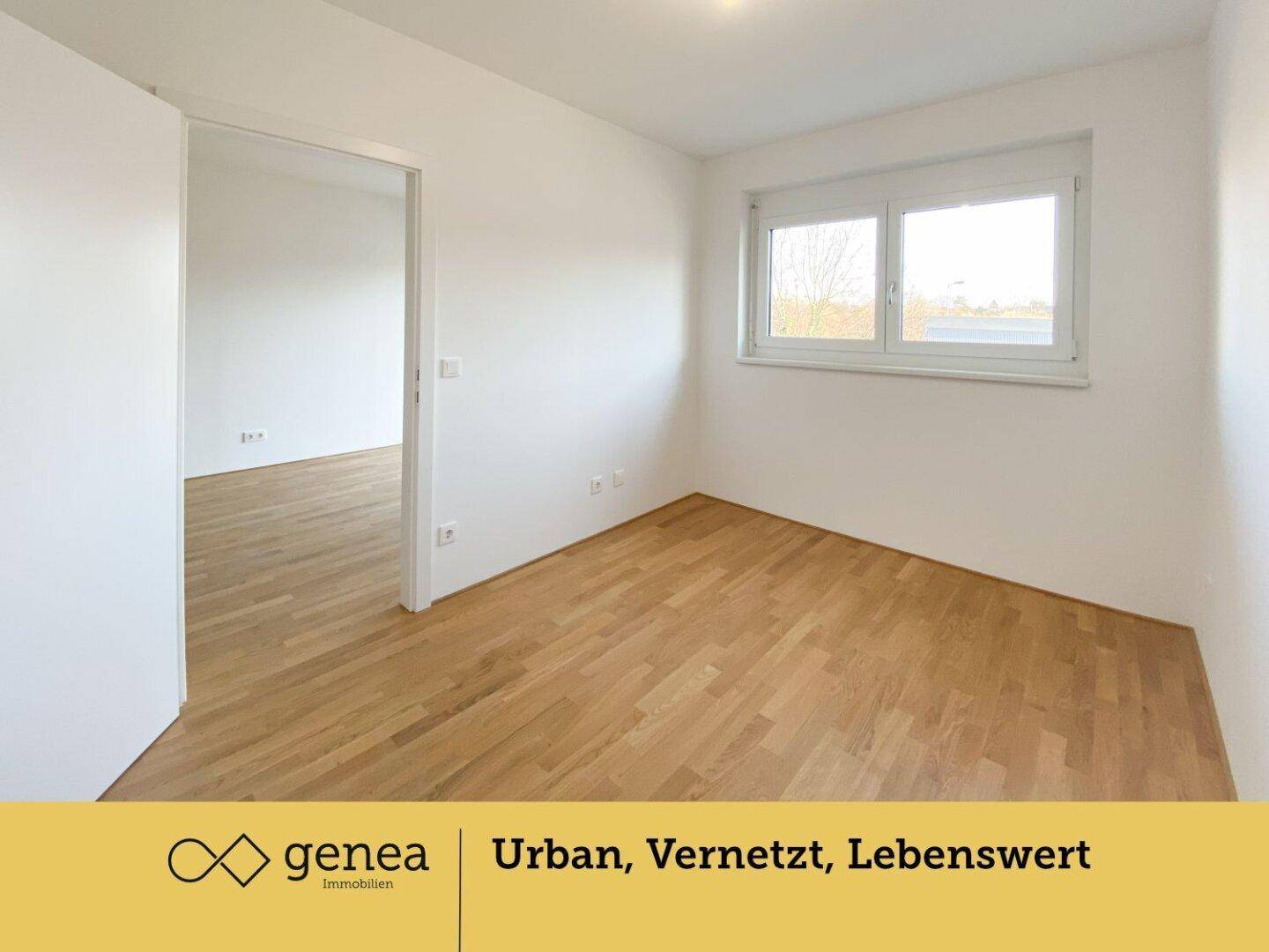 Helles Schlafzimmer mit Parkettboden und Fenster, das einen Blick nach draußen bietet.