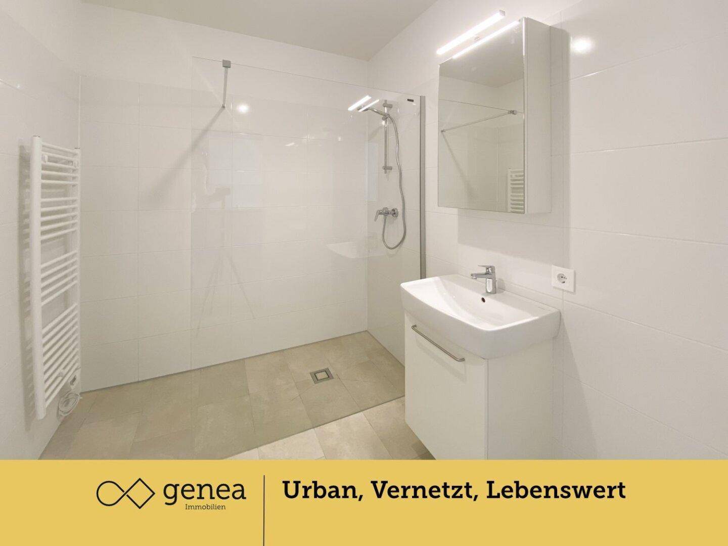Modernes Badezimmer mit ebenerdiger Dusche, weißen Fliesen und beheiztem Handtuchhalter.