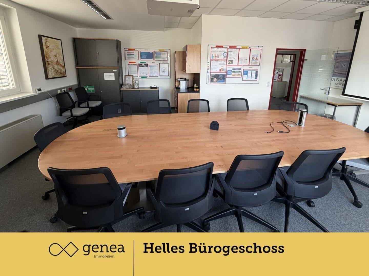 Konferenzraum mit großem Holztisch, Bürostühlen und Whiteboards an der Wand für Besprechungen.