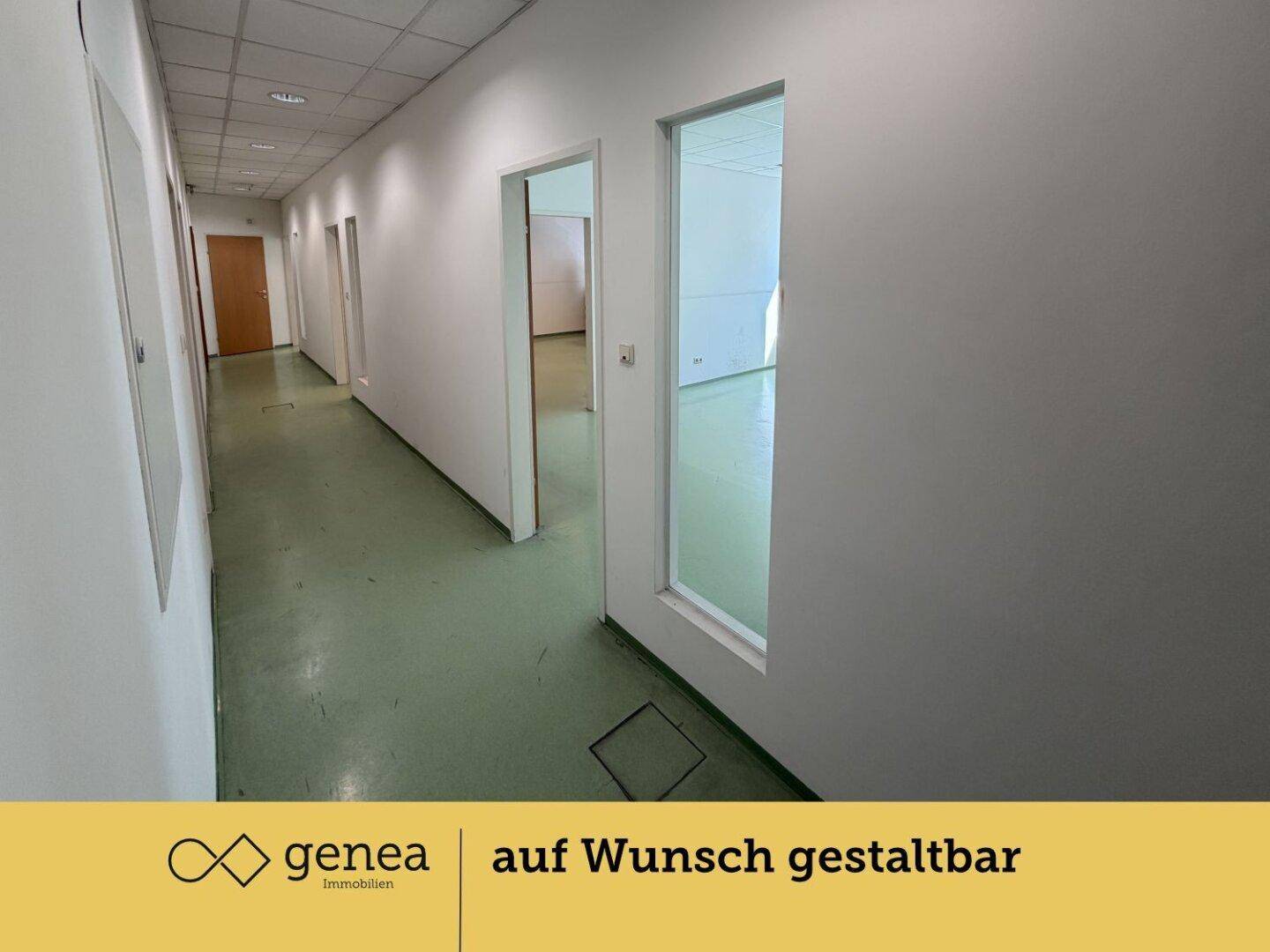 Langer Flur mit grünem Bodenbelag und mehreren Türen zu Büroräumen.